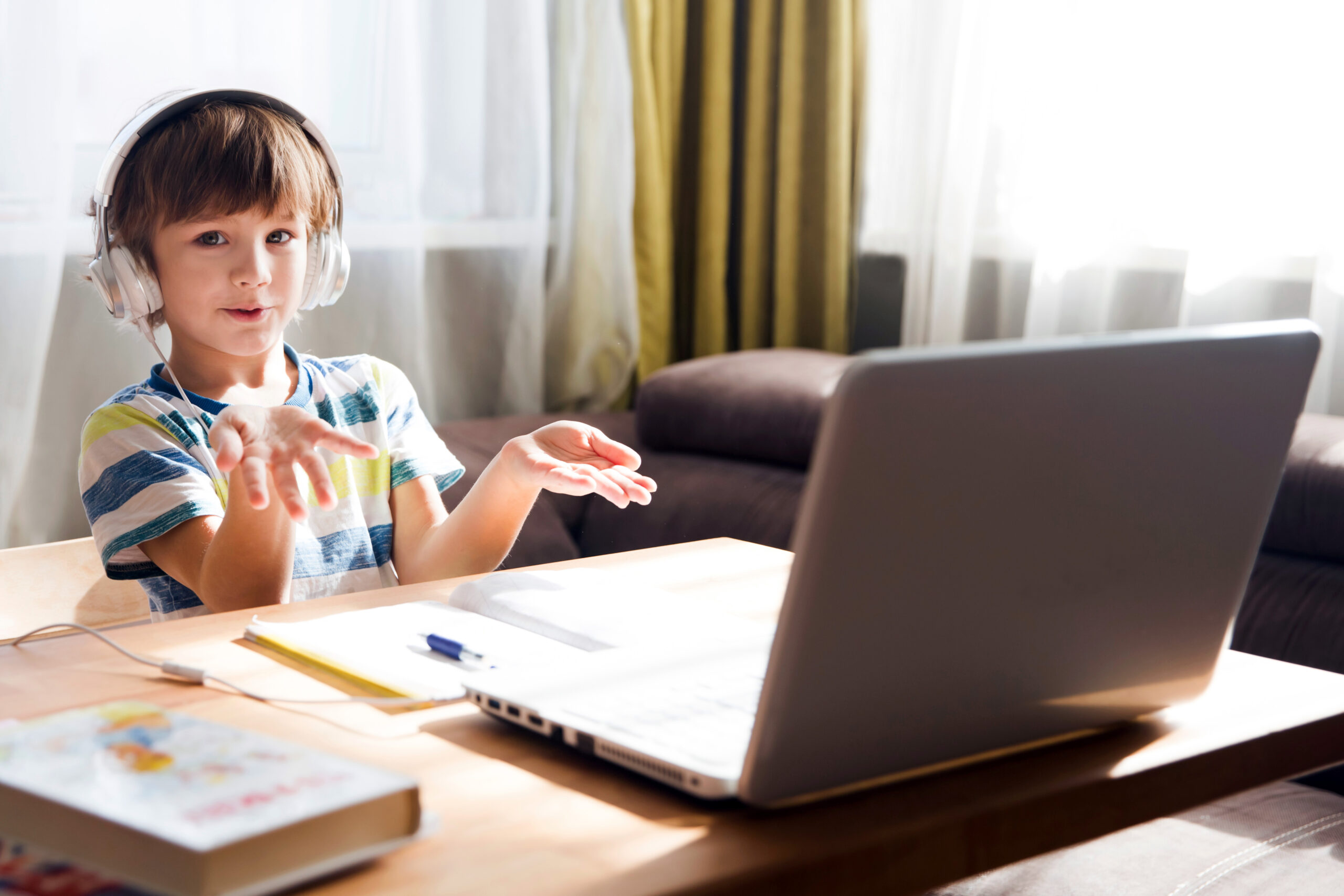 child boy in headphones is using a laptop and study online with